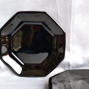 May include: Two black octagonal ceramic plates. The plates are glossy and have a slightly raised edge.