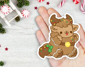 May include: A gingerbread creature with brown fur, a brown gingerbread body, and green and red sprinkles. The creature has a big smile and is wearing a gold belt. The creature is holding a green bow in its right hand.
