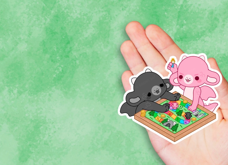 K&ouml;nnte beinhalten: Ein schwarzer und rosa Drache spielt ein Brettspiel mit einem bunten Spielbrett und Spielfiguren. Das Spielbrett hat einen Pfad mit einem Schloss, einem Berg und einem Baum.