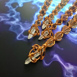 May include: Three long, slender wands crafted from copper wire wrapped around clear, pointed quartz crystals. The wire forms a repeating, intricate lattice pattern along the length of each wand, securing the crystals in place at regular intervals.