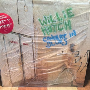 Puede incluir: Un álbum de vinilo de Willie Hutch, titulado "Concert in Blues", con letras de estilo graffiti. La portada del álbum presenta una pegatina roja que dice "Party Down". El álbum está sellado en plástico.
