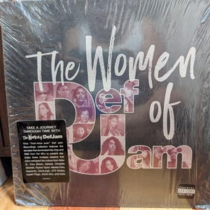 May include: A vinyl record album titled "The Women of Def Jam" in a plastic sleeve. The album cover features a collage of women's faces and the Def Jam logo. A sticker on the front reads "Take a Journey Through Time with The Women of Def Jam."