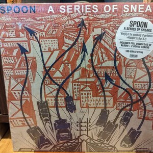 Peut inclure: Un album vinyle intitulé "Spoon: A Series of Sneaks". La couverture de l'album présente une illustration d'une ville avec des flèches et des véhicules dans des tons orange, bleu et blanc. L'album comprend un téléchargement complet de l'album et deux titres bonus.