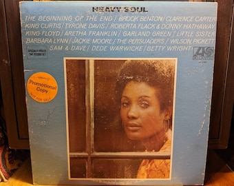 May include: A blue and white record album cover with the title "Heavy Soul" and a photo of a woman with dark hair and brown eyes. The album features artists such as Brook Benton, Clarence Carter, King Curtis, Tyrone Davis, Roberta Flack, and Donny Hathaway. The album is a promotional copy and is not for sale.