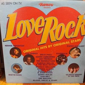 May include: A vintage vinyl record album cover featuring a red heart with the words "Love Rock" in yellow lettering. The album cover features a collection of original hits by artists such as Minnie Riperton, Boz Scaggs, Lou Rawls, Billy Paul, Keith Carradine, Ian Thomas, The Manhattans, Harold Melvin & The Blue Notes, Deniece Williams, Morris Albert, Darryl Hall & John Oates, Kenny Nolan, Dan Hill, The Hollies, Blood, Sweat & Tears, Starbuck, Patsy Gallant, and Gladys Knight & The Pips.
