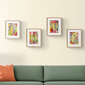 May include: Four framed art prints spelling out the word "LOVE" in yellow letters on a colorful background. The frames are light brown wood.