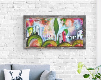 May include: A colorful painting of a whimsical village with houses, trees, and flowers. The painting is framed in a rustic wooden frame and hangs on a white brick wall.