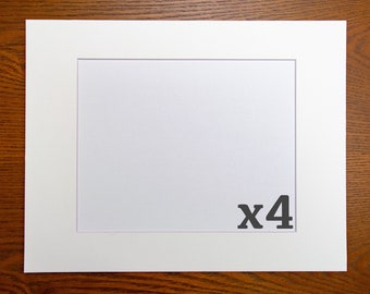 May include: A set of four white mat boards with a white core, each measuring 11x14 inches. The mat boards are designed to be used with standard 8x10 inch photos.