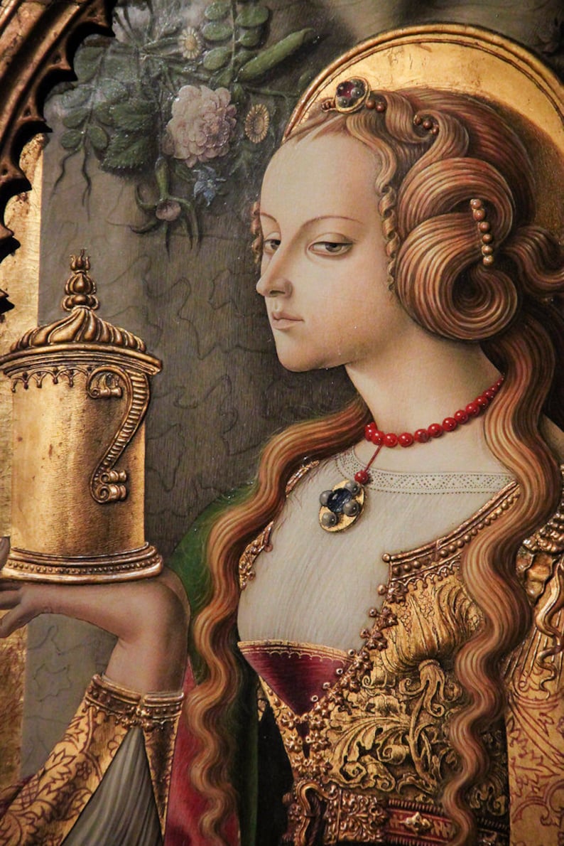 Pu&ograve; includere: Un dipinto in stile rinascimentale raffigura una donna con lunghi capelli rossi ondulati e un'aureola dorata. Indossa un abito ricamato in oro e una collana di perline rosse con un ciondolo. Tiene in mano un vaso d'oro con un manico ornato.