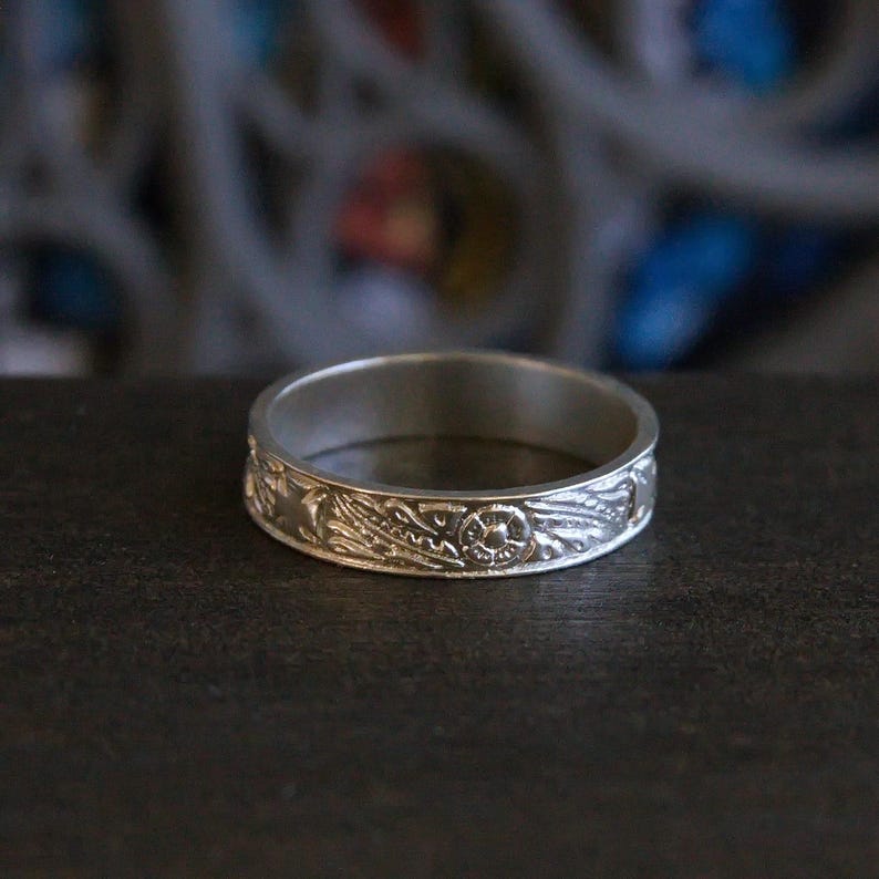 Pu&ograve; includere: Un anello a fascia d'argento con un intricato design floreale.