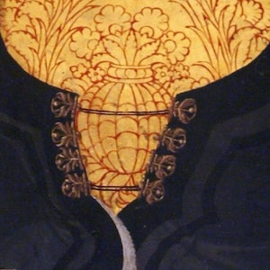 May include: A close-up of a black velvet garment with gold buttons. The buttons are ornate and have a floral design. The garment is decorated with a gold and red floral pattern.