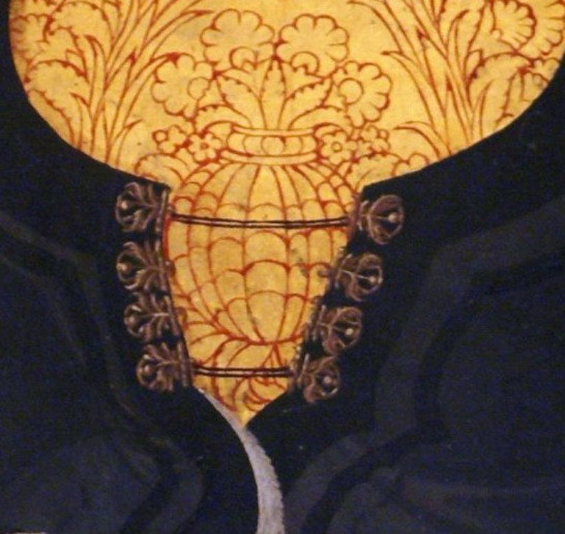May include: A close-up of a black velvet garment with gold buttons. The buttons are ornate and have a floral design. The garment is decorated with a gold and red floral pattern.