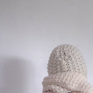 May include: A white crocheted hat and scarf set. The hat is a slouchy beanie style and the scarf is a long, rectangular shape.