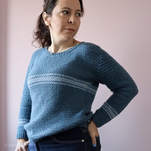 Blue crochet sweater pattern seen from front with light blue horizontal stripes.
