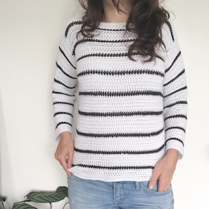May include: A white and black striped crocheted sweater with long sleeves.