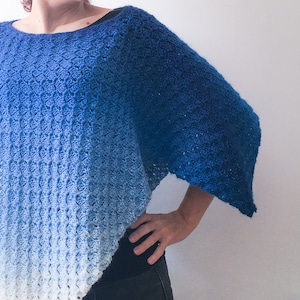 May include: A blue and white ombre crochet poncho with a loose fit and a wide neckline.