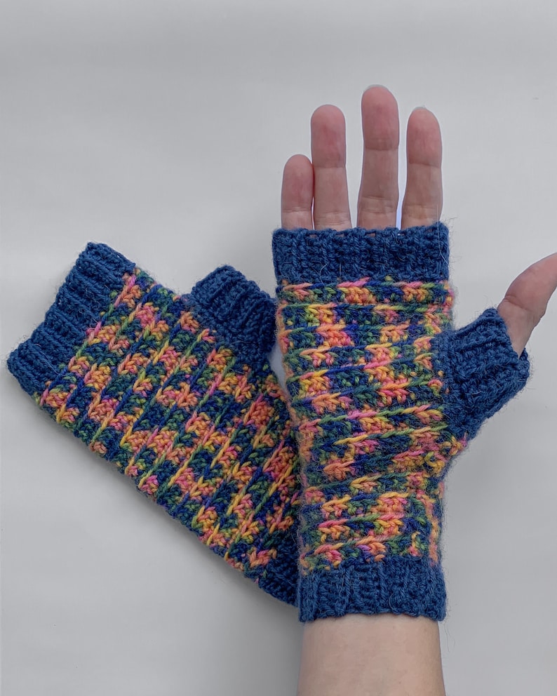 May include: A pair of blue fingerless gloves with a pink, yellow, and green geometric pattern.
