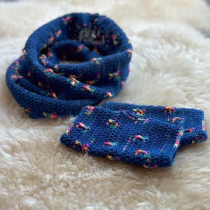 May include: A blue crocheted infinity scarf and matching wrist warmers with colorful flecks throughout.