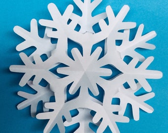 May include: A white paper snowflake with six points, each point having a cut-out design. The snowflake is layered, creating a three-dimensional effect.