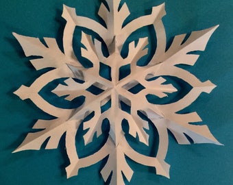 May include: A white paper snowflake with intricate cutouts, against a teal blue background.