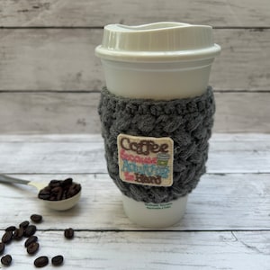 May include: Grey crocheted coffee cup cosy with a white embroidered patch that says "Coffee because adulting is hard".