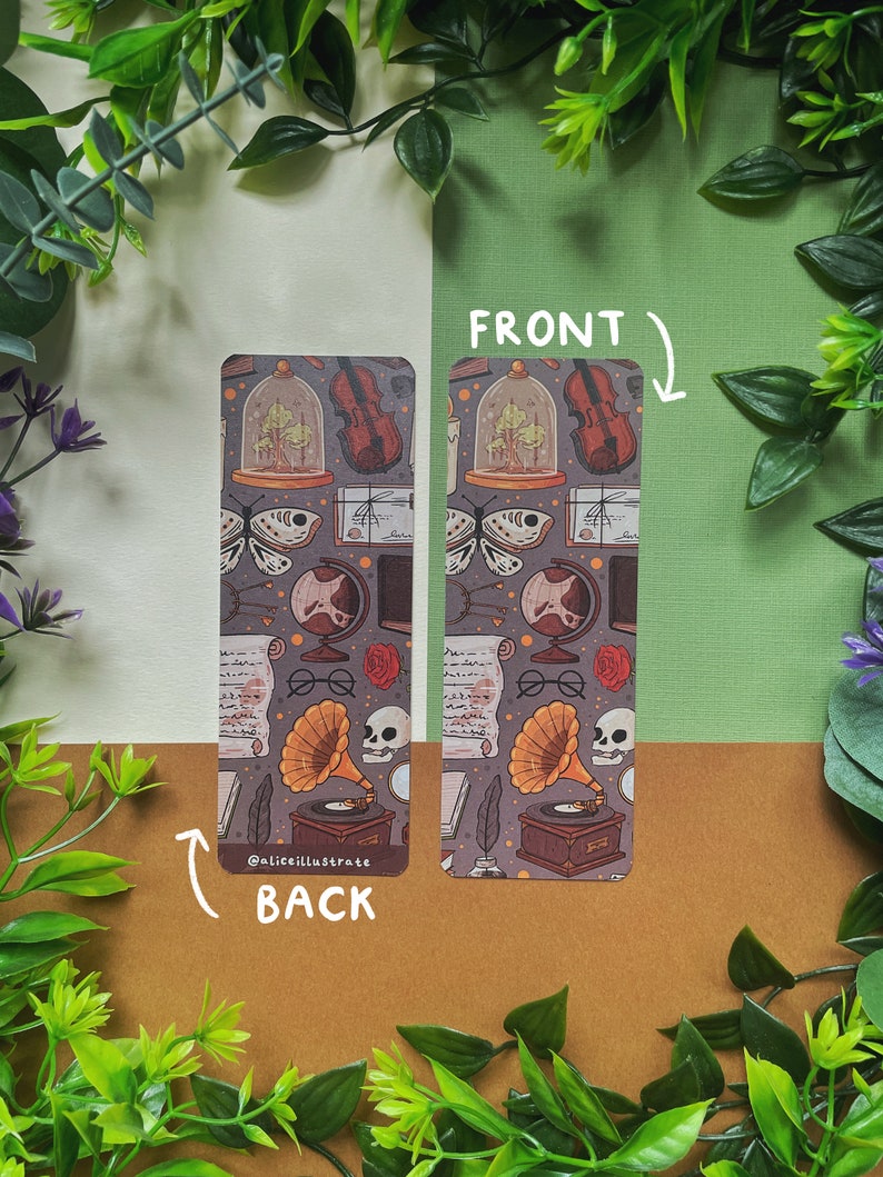 May include: A double-sided bookmark with a vintage aesthetic. The front features a repeating pattern of a violin, a globe, a skull, a magnifying glass, a rose, a book, a feather, and a glass dome with a tree inside. The back features the same pattern with the addition of a gramophone and the text "@aliceillustrate".