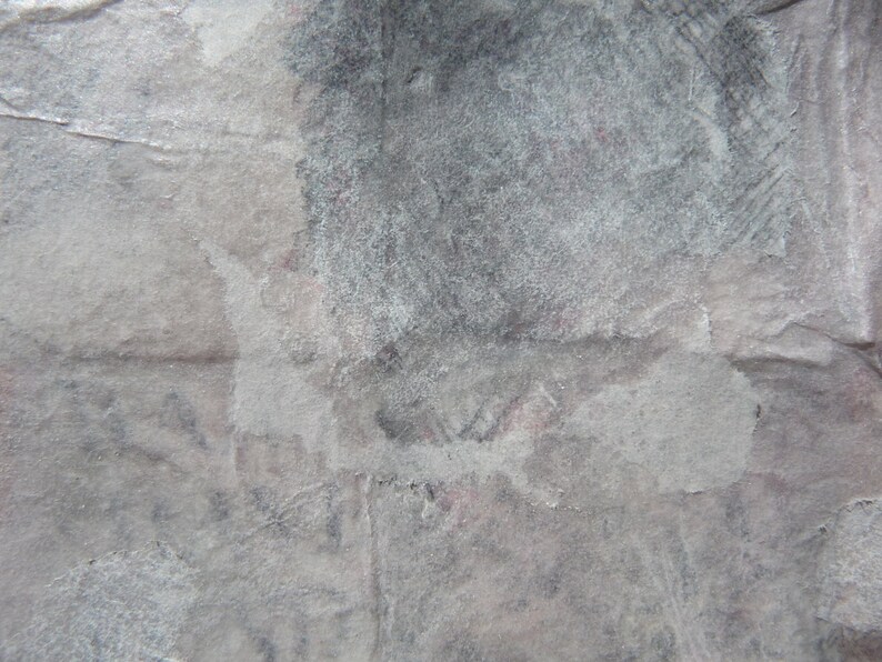 May include: A close-up of a textured, gray surface with a white, faded, and slightly textured area. The surface appears to be made of paper or cardboard.