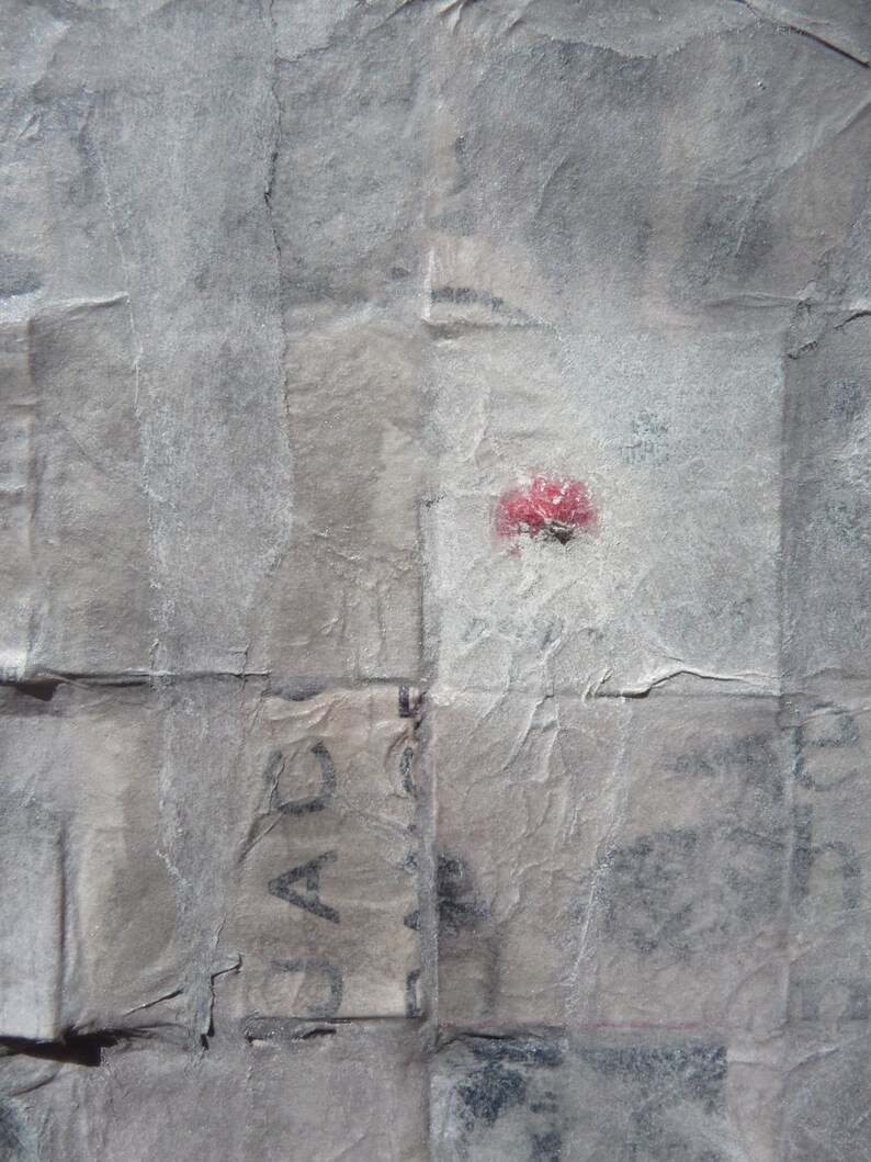 May include: A close-up of a crumpled piece of paper with a red dot and the word "JAC" visible.