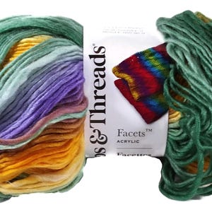 May include: A skein of Loops & Threads Facets acrylic yarn featuring a variegated color palette of green, yellow, purple, and orange. The white paper label displays the brand name and product line, with a small graphic showing a rainbow-colored swatch.