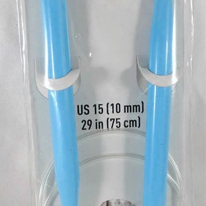 May include: A pair of light blue Loops & Threads circular plastic knitting needles in original packaging. The needles are US 15 (10 mm) in size with a 29 inch (75 cm) cable. The packaging includes the brand name and product specifications.