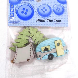 May include: A package of "Dress It Up" button assortments for crafting. The package includes a light blue camper, a white tent, and green trees. The text "Hittin' The Trail" is printed on the package.