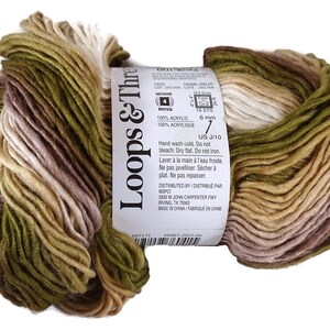 Puede incluir: Una madeja de hilo Loops & Threads de peso medio 4 con una paleta de colores variados en verde oliva, bronceado, marr&oacute;n y crema. La etiqueta de papel blanco muestra detalles del producto, incluyendo 100% acr&iacute;lico y un tama&ntilde;o de 6 mm.