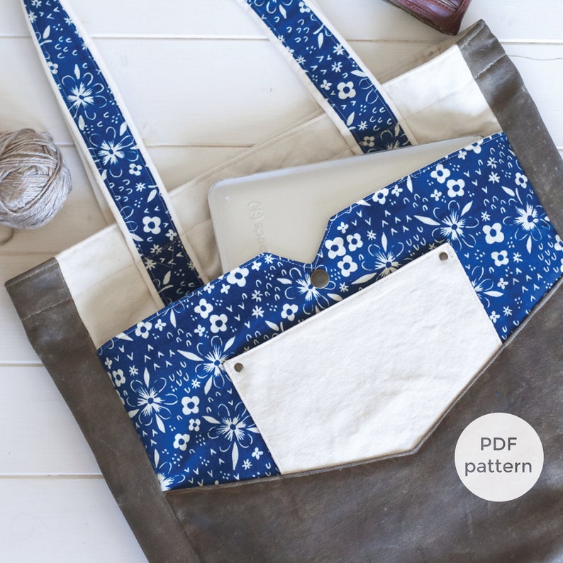 May include: A gray tote bag with white and blue floral patterned accents. The bag features a blue floral pocket and straps, and a white pocket. The text "PDF pattern" is visible on the bag.