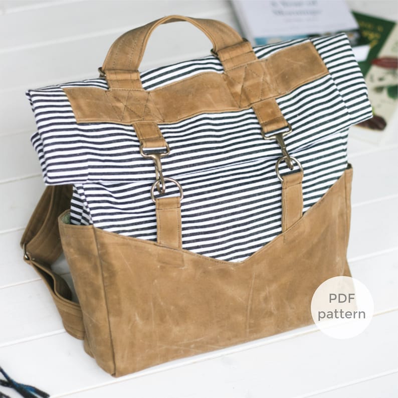 K&ouml;nnte beinhalten: Ein brauner und wei&szlig; gestreifter Canvas-Rucksack mit braunen Lederriemen und Schnallen. Der Rucksack hat einen Rollverschluss und ein gro&szlig;es Fach auf der Vorderseite. Der Text "PDF pattern" ist in der unteren rechten Ecke des Bildes sichtbar.