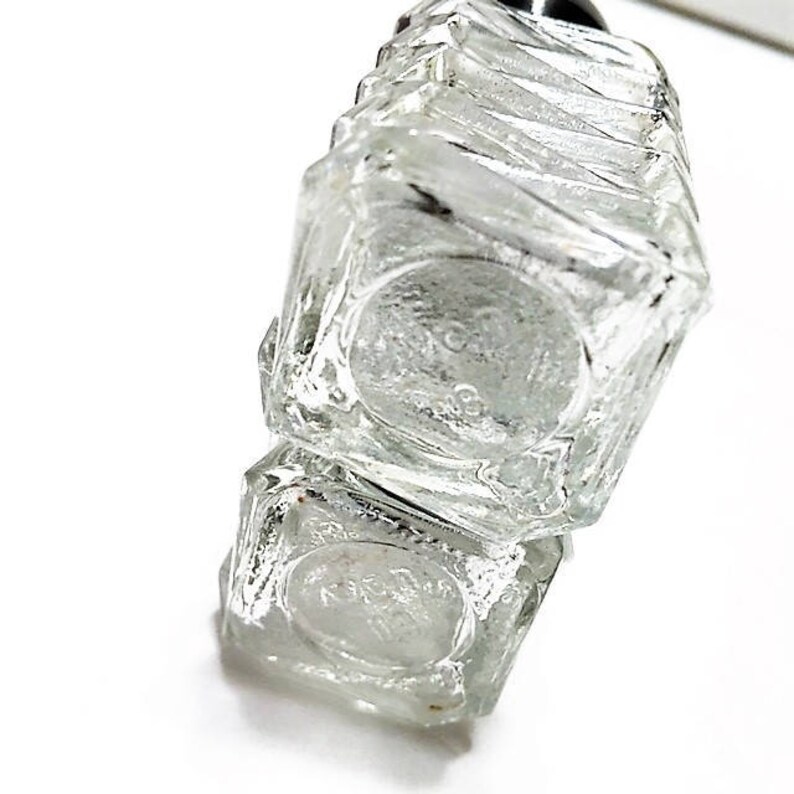 May include: A clear glass bottle with a textured surface. The bottle is stacked on top of another clear glass bottle with a textured surface.