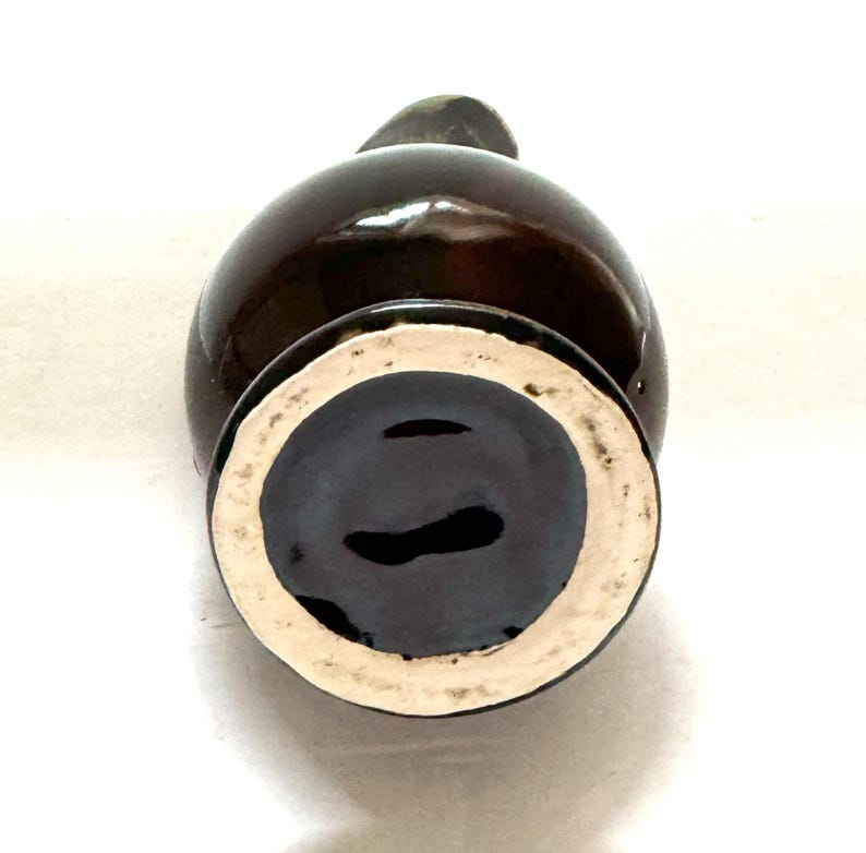 May include: The bottom of a brown ceramic pitcher with a white glazed rim.
