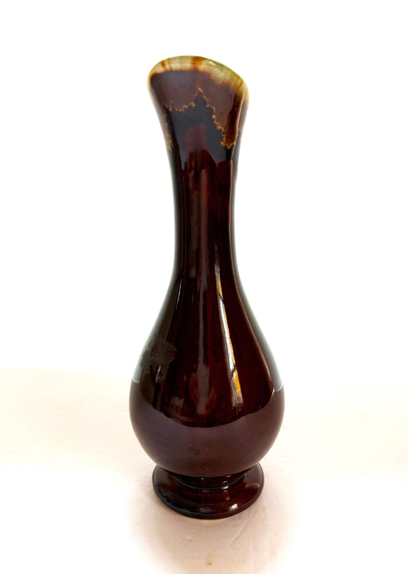 May include: A brown ceramic vase with a flared opening and a rounded base. The vase has a glossy finish and a subtle marbled pattern.