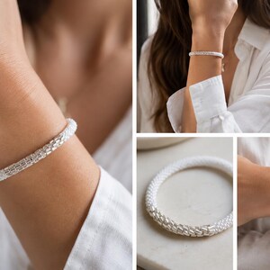 Puede incluir: Una pulsera flexible que presenta una combinación de cuentas blancas y segmentos metálicos de tono plateado. El diseño consiste en un patrón repetitivo de secciones de cuentas blancas que alternan con eslabones plateados texturizados.