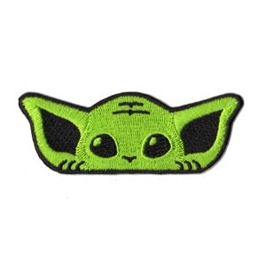 May include: Embroidered patch featuring a stylized green alien face with large black eyes and ears. The patch has a black border and is set against a white background. The alien's face is a bright, vibrant green.