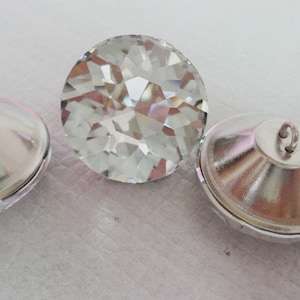 Peut inclure: Quatre boutons en cristal transparent avec dos argentés. Deux des boutons ont une boucle au dos pour la couture.