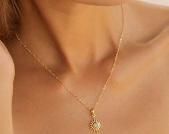 May include: A gold necklace and a matching gold hoop earring, both featuring a sunburst pendant with a central iridescent stone. The sunburst design consists of thin, radiating rays surrounding the circular gemstone, crafted in a polished gold tone.