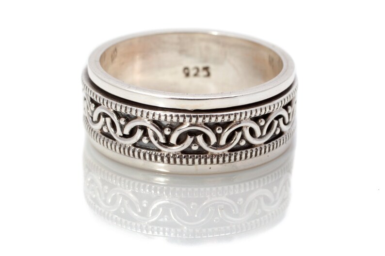 May include: A silver ring with a detailed, intricate design of interlocked circles and dots. The ring is marked with the number "925" on the inside.