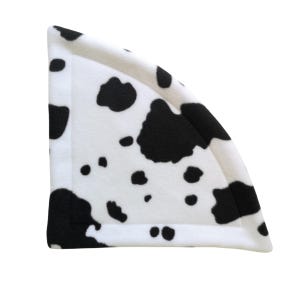 May include: A triangular corner fleece pad featuring a white base with an irregular black cow print pattern. The fabric has a soft texture and includes a stitched border along the edges, creating a defined shape for use in small animal enclosures.
