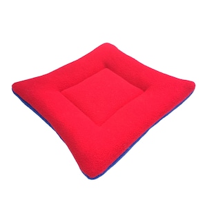 May include: A red square pet bed with a blue border. The bed is made of soft fleece material.