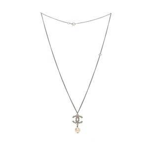 May include: Silver-toned necklace featuring a pendant with a double-C design encrusted with small, clear crystals. A single, round, white pearl dangles below the pendant. The necklace has a delicate chain and a clasp closure.