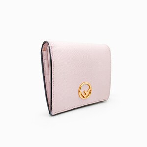 May include: A pale pink leather wallet with a gold Fendi logo. The wallet has a fold-over closure and a small pocket on the front.