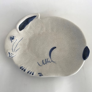 May include: A white ceramic plate shaped like a rabbit with blue painted details. The plate has a crackled glaze finish.