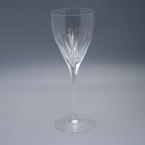 May include: A clear glass wine glass with a tall stem and a wide bowl. The bowl has a decorative pattern of lines.