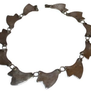 May include: Silver bracelet with a chain and multiple silver charms in the shape of a leaf.
