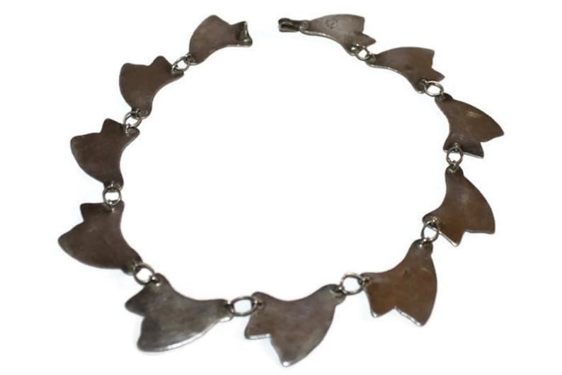 May include: Silver bracelet with a chain and multiple silver charms in the shape of a leaf.